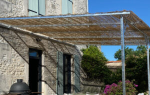 Structure de pergola en acier galvanisé 5 x 3,5 m fixée sur un mur en moellons à Saint-Brice